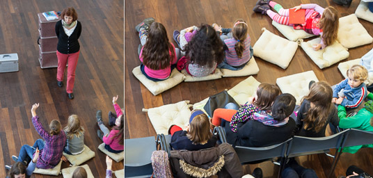 Sylvia Schopf bei einer Veranstaltungen mit aufmerksamen Kindern im Publikum, die teils auf Stühlen, teils auf Sitzkissen auf dem Boden sitzen.